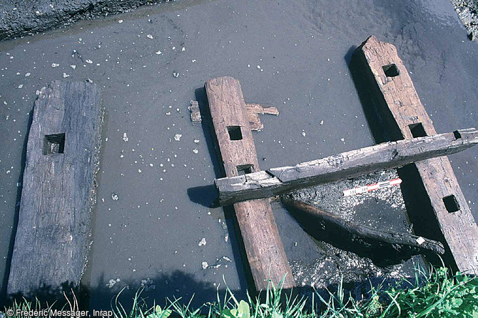 Poutres en orne et en chêne assemblées par tenons et mortaises, formant une passerelle permettant de franchir le fossé en direction du sud, seconde moitié du XIe s., Pineuilh (Gironde), 2003.   