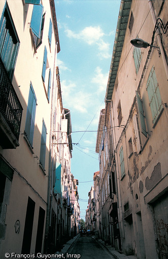 Rue de l'Anguille à Perpignan (Pyrénées-Orientales), issue d'un programme de lotissement médiéval, 1999.  La rue de l'Anguille s'inscrit dans un programme d'aménagement d'un lotissement à la fin du XIIIe s. : une trame régulière est mise en place, définissant des maisons de 45 à 50 m2 de superficie au sol.  