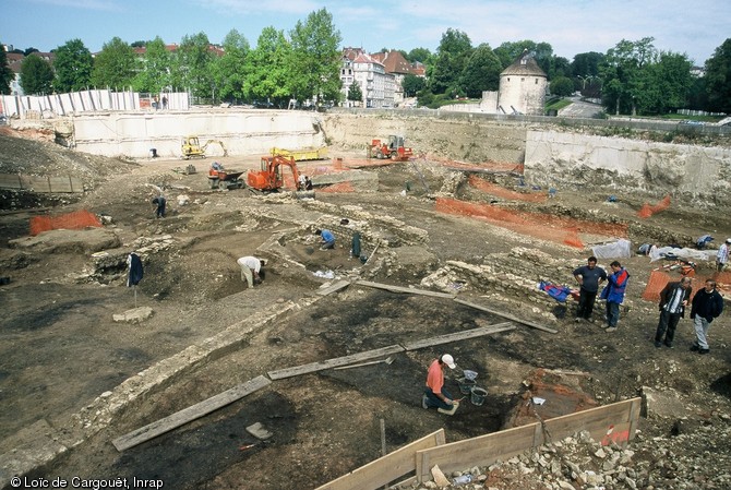 Vue générale des fouilles effectuées en bordure du Doubs à Besançon (Doubs) en 2001-2002 avec au premier plan une « halle artisanale » dévolue au travail du verre qui a été en activité entre le dernier tiers du Ier siècle et la fin du IIe siècle de notre ère. Elle était disposée en bordure d’une voie qui la séparait de la berge antique du Doubs.    