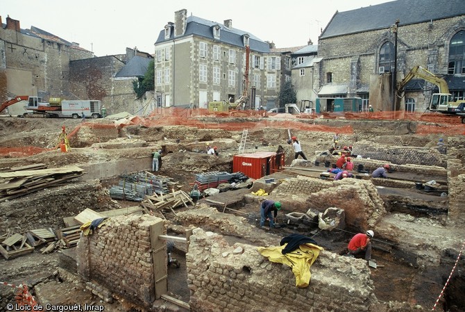 Vue générale du chantier avec, au premier plan, les vestiges des boutiques gallo-romaines établies en bordure d'une grande rue où travaillaient des artisans.