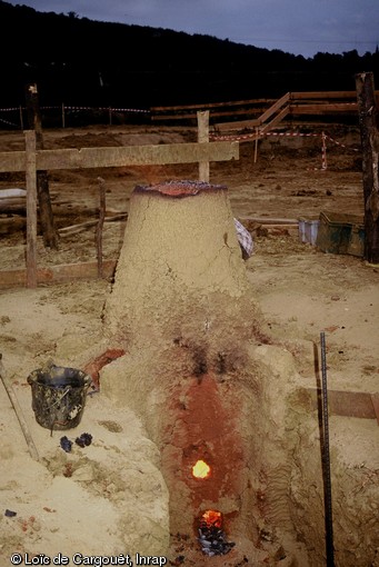 Reconstitution expérimentale de bas fourneaux organisée en juillet 1997 à la suite de la découverte de nombreux bas fourneaux sur l'emprise de l'autoroute A28 dans le secteur du Mans (Sarthe).  Une coulée en fusion s'échappe du bas fourneau expérimental.  