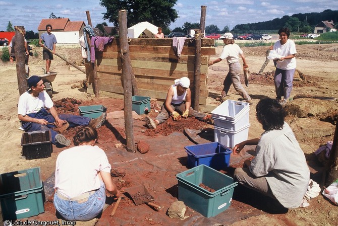 Atelier de concassage du minerai de fer organisé lors d'une expérimentation de production du fer effectuée en juillet 1997 suite à la découverte de nombreux bas fourneaux sur l'emprise de l'autoroute A28 dans le secteur du Mans (Sarthe) en 1996-1997.  Le minerai, préalablement  grillé , (les blocs extraits du sol sont brûlés dans un feu de bois) est dans un second temps concassé pour être finalement jeté dans la gueule des fours. 