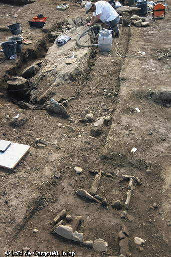 Dégagement d'un menhir sur la fouille de la nécropole du Néolithique moyen de Thonon-Les-Bains (Haute-Savoie) fouillée en 2004. Au premier plan deux sépultures en coffre de pierre.