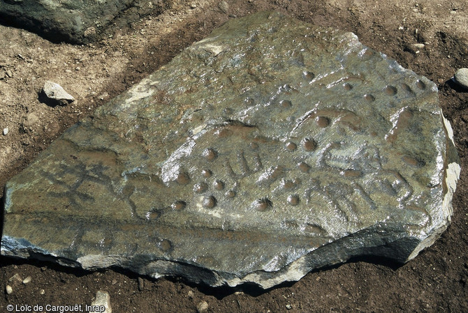 Pierre ornée de dessins et de cupules. Elle était utilisée en réemploi comme dalle de couverture d'une sépulture en coffre. Fouille de la nécropole néolithique de Thonon-les-Bains (Haute-Savoie) en 2004.