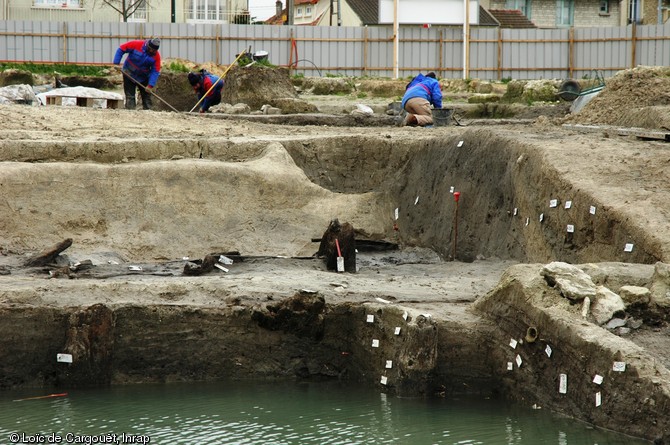 Vue en coupe du site de Chelles (Seine-et-Marne), 2007.  Au premier plan se distingue le quai gaulois dat&eacute; du Ier s. avant notre &egrave;re, au second plan appara&icirc;t une couche de s&eacute;diments ayant provoqu&eacute; l'envasement de ce bras de la Marne et enfin, au troisi&egrave;me plan, appara&icirc;t la berge o&ugrave; s'est d&eacute;velopp&eacute; un petit &eacute;tablissement agricole carolingien. 