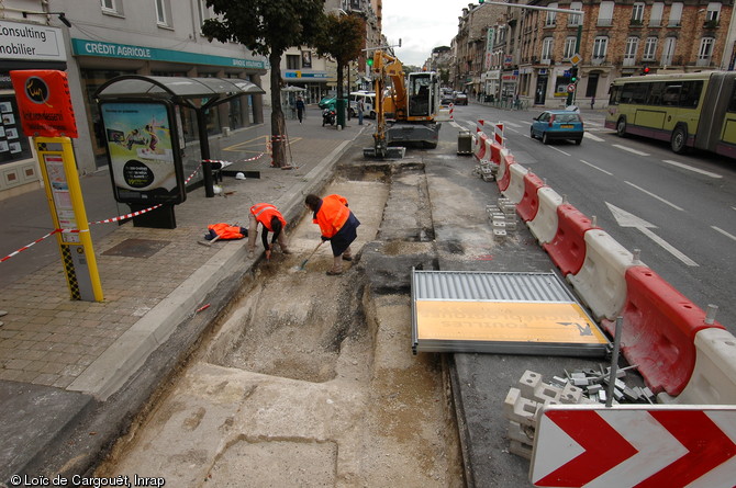 Sondage pratiqué sur le tracé du tramway rue de Laon à Reims (Marne), 2007-2008.  Plusieurs opérations ont été menées sur différents secteurs du tracé et comme ici, les contraintes ont été nombreuses : calendrier serré, fouilles simultanées, circulation dense... 