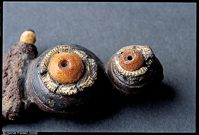 Fibule ou broche de fer, de corail et d'or qui fixait les vêtements d'une princesse gauloise de la nécropole de Bucy-le-Long (Aisne), Ve-IVe s. avant notre ère. Fouille de 1991-1994.  Cet objet, antérieur d'un siècle au reste de la parure, s'est donc transmis pendant plusieurs générations. 