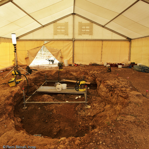 Vue de la fouille de la s&eacute;pulture collective du N&eacute;olithique final sur le site du Mas Rouge/La Cavalade &agrave; Montpellier (H&eacute;rault), 2013.  Cette s&eacute;pulture a &eacute;t&eacute; d&eacute;couverte aux abords du village n&eacute;olithique pr&eacute;c&eacute;demment fouill&eacute;. La cavit&eacute;, partiellement sous-cav&eacute;e est de plan rectangulaire, creus&eacute;e dans des bancs gr&eacute;seux plus ou moins compact. 