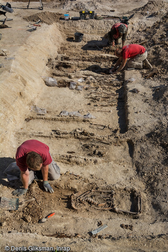 Fouille en cours d'une sépulture multiple découverte dans un cimetière militaire allemand de fortune de la Grande Guerre dans le village de Boult-sur-Suippe, Marne (2016).   Selon la motalité journalière, les sépultures sont individuelles, doubles ou multiples, et peuvent contenir jusqu'à douze individus. 