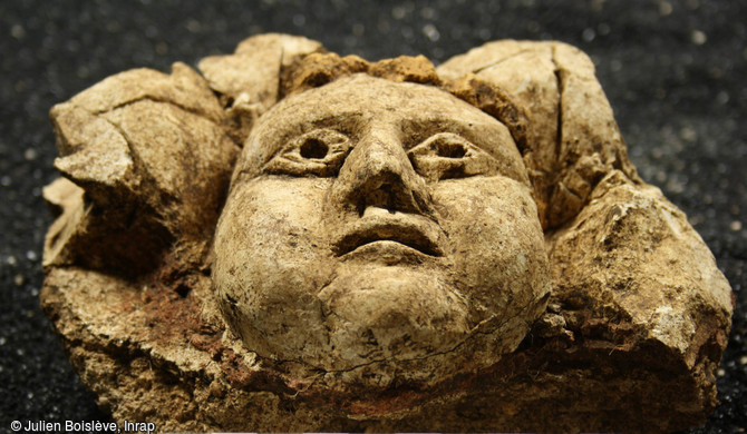 Visage aux traits juvéniles et aux cheveux blonds cernés de feuillages découvert à Entrains-sur-Nohain (Bourgogne).