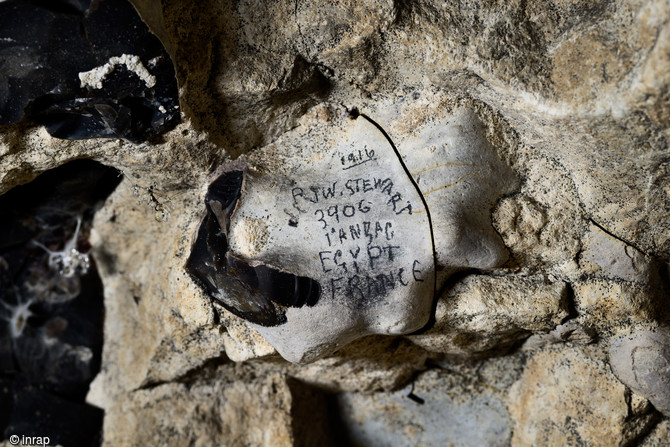 Inscription  du soldat australien de la Grande Guerre James Warren Stewart retrouvée dans la grotte souterraine de Naours (Somme), 2016.  1916, P(pour private, soldat) J(ames) W(arren) Stewart, 3906 (matricule) 1er ANZAC campagne d'Egypte et de France.  Enrôlé en 1916 dans le « Second ANZAC Cyclist Battalion ». Il rejoindra l’Australie le 20 mai 1919. Le chiffre 3906 qui apparait sur l’inscription correspond à son numéro de matricule.