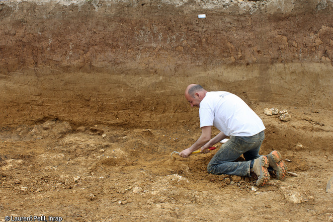 Archéologue dégageant une concentration de silex taillés sur le site du Paléolithique moyen récent (entre 110 000 et 70 000 ans) à Tigery (Essonne), 2016