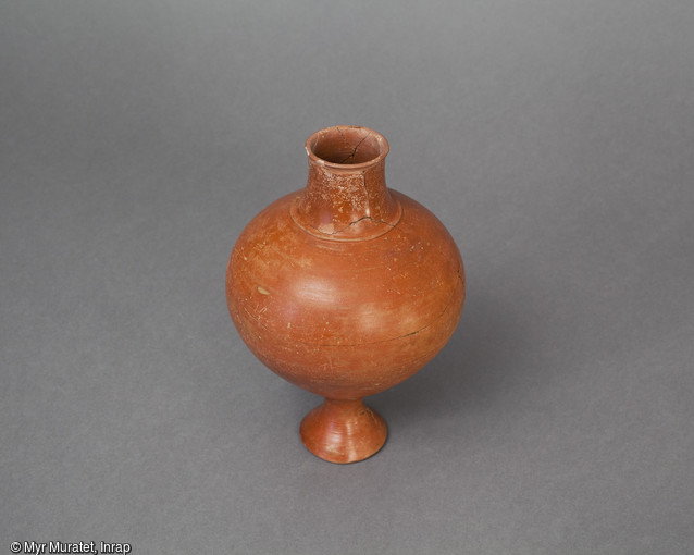 Bouteille en céramique à pâte brune et englobe rouge lustré, datée du 1er siècle de notre ère, hauteur : 21 cm,  provenant du site de l'Îlot de la Charpenterie à Orléans (Loiret). Inspirée des vases  balustres  gaulois, elle témoigne des persistances de la culture gauloise près d'un siècle après la conquête romaine. 