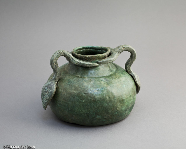 Vase en bronze à 2 anses, Ier-IIe siècle, hauteur 14 cm, mis au jour dans le sanctuaire du site de la ZAC du Clos de la Fontaine de l'Étuvée à Orléans (Loiret). Le fond était initialement muni de trois pieds scellés au plomb, qui ont disparu. Il a été découvert enfoui dans une fosse aménagée dans le sanctuaire. Ces enfouissements volontaires d'objets liés au culte montrent que ces derniers, désormais non-utilisés, ne sont pas pour autant désacralisés et restent attachés au sanctuaire.