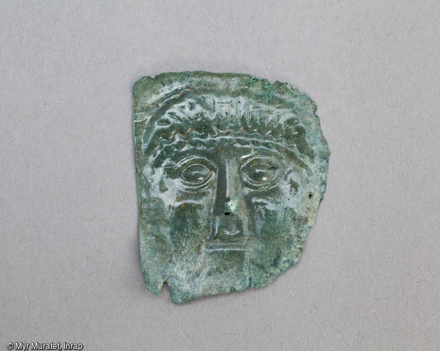 Ex-voto en tôle de bronze martelée représentant un visage, Ier-IIe siècle, mis au jour dans le sanctuaire du site de la ZAC du Clos de la Fontaine de l'Étuvée à Orléans (Loiret). Plutôt que d'y voir une représentation de la divinité, c'est sans doute l'image même du dédicant s'adressant à son dieu qu'il faut ici considérer. Les ex-voto sont des objets déposés dans le sanctuaire, soit à titre de supplique, soit en remerciement d'une guérison. Ils attestent une vocation thérapeutique du sanctuaire.