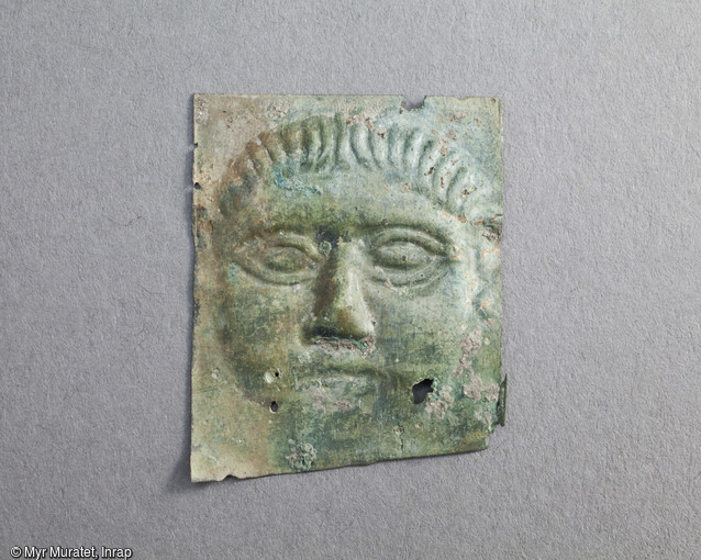 Ex-voto en tôle de bronze martelée représentant un visage, Ier-IIe siècle, mis au jour dans le sanctuaire du site de la ZAC du Clos de la Fontaine de l'Étuvée à Orléans (Loiret). Plutôt que d'y voir une représentation de la divinité, c'est sans doute l'image même du dédicant s'adressant à son dieu qu'il faut ici considérer. Les ex-voto sont des objets déposés dans le sanctuaire, soit à titre de supplique, soit en remerciement d'une guérison. Ils attestent une vocation thérapeutique du sanctuaire.