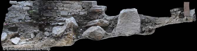 Tranch&eacute;e de r&eacute;cup&eacute;ration du rempart du XIIIe s, Mont-Saint-Michel (Manche), 2017. Le comblement de la tranch&eacute;e se caract&eacute;rise par un s&eacute;diment brun dans lequel on voit des blocs de granit de grande taille. Elle vient couper le cimeti&egrave;re qui s'installe sur un niveau naturel de sable orang&eacute;&nbsp;