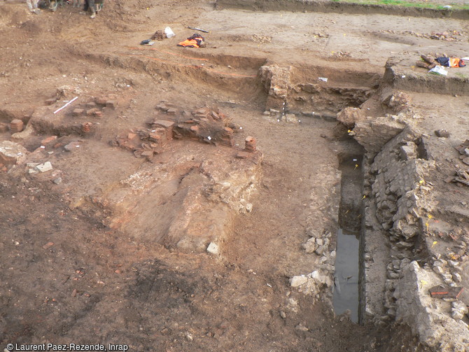 Fouille des thermes gallo-romains &agrave; Portbail (Manche). A droite : &eacute;gout servant &agrave; l'&eacute;vacuation de l'eau des thermes (piscines, baignoires...) ; au premier plan chaufferie ; &agrave; l'arri&egrave;re-plan : pilettes d'hypocauste.