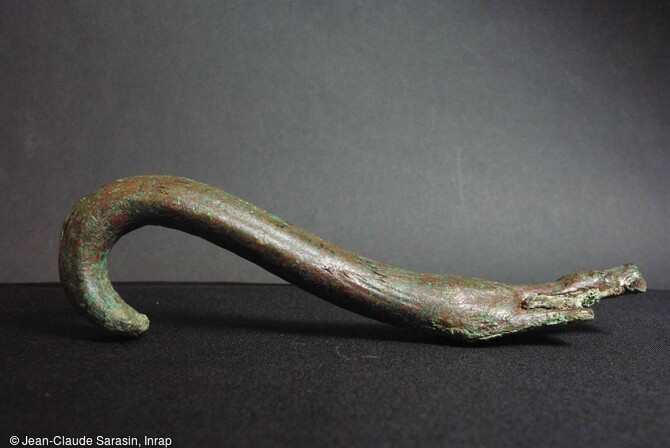 L'anse de l'authepsa d&eacute;couverte &agrave; Die (Dr&ocirc;me) se termine dans sa partie basse par la repr&eacute;sentation d'un chien allong&eacute;. R&eacute;alis&eacute;e &agrave; la cire perdue, cette anse pr&eacute;sente des d&eacute;tails anatomiques remarquables. Le reste de l'anse est orn&eacute; d'une s&eacute;rie de cannelures verticales et d'une stylisation du pelage de l'animal. 