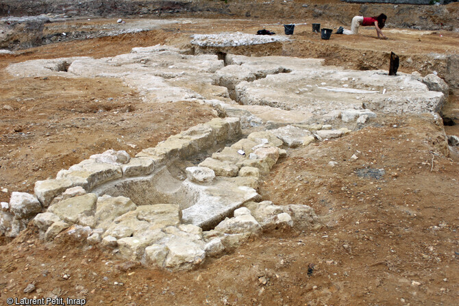L'ancienne gare du Pecq (Yvelines) en cours de fouille en 2017. R&eacute;ceptacle d'une grue hydraulique a &eacute;t&eacute; mis au jour, livrant une magnifique vasque taill&eacute;e dans un important bloc de calcaire. Au second plan les fondations des plaques de retournement des locomotives. 