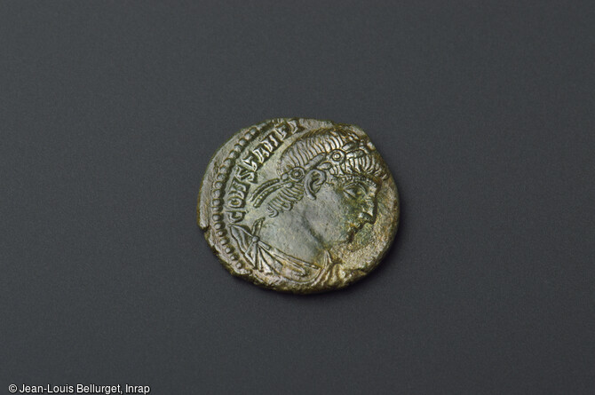 Face d'une monnaie en bronze, frapp&eacute;e en 335-336, repr&eacute;sentant l'empereur Constantin 1er. Au revers, deux soldats arm&eacute;s et casqu&eacute;s tiennent des enseignes militaires. D&eacute;couverte lors de la fouille de la Zac Pasteur &agrave; Besan&ccedil;on (Doubs) entre 2010 et 2011.