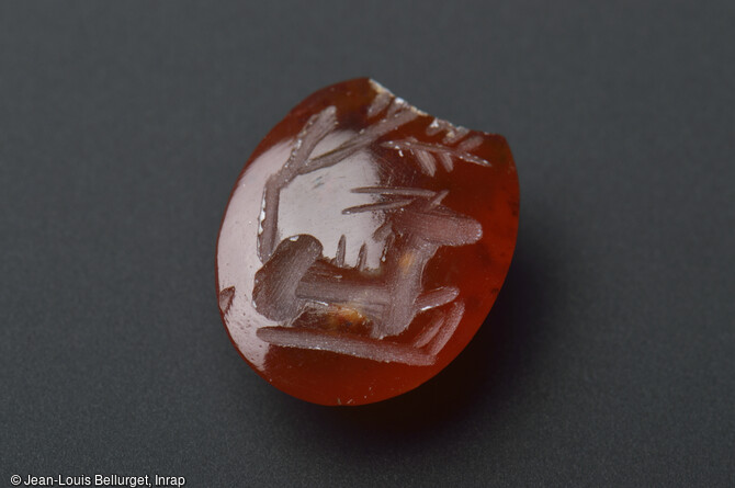Intaille en cornaline, 150-200 de notre &egrave;re, mise au jour lors de la fouille de la Zac Pasteur &agrave; Besan&ccedil;on (Doubs) entre 2010 et 2011. Ce petit objet, d&eacute;cor&eacute; d'une ch&egrave;vre couch&eacute;e sous un arbre (d&eacute;cor en creux) est un chaton qui &eacute;tait serti sur l'anneau d'un bague. 