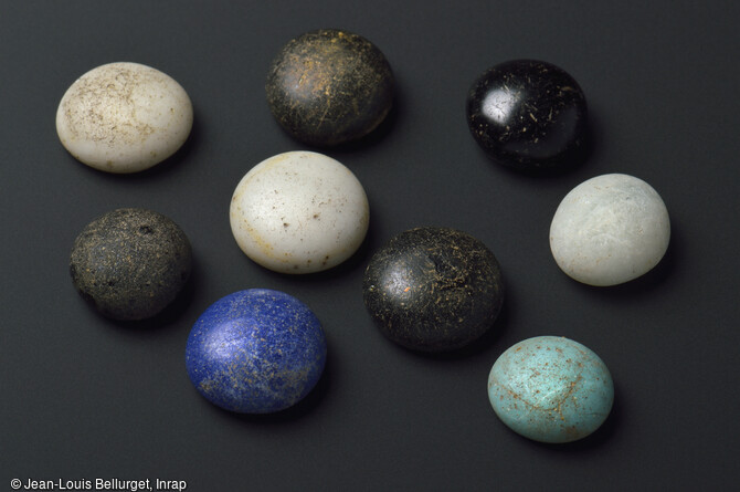 Jetons de jeu en p&acirc;te de verre, mis au jour lors de la fouille de la Zac Pasteur &agrave; Besan&ccedil;on (Doubs) entre 2010 et 2011. Ces petits objets pr&eacute;sentant une face plane et une face bomb&eacute;e servaient de pions pour diff&eacute;rents jeux de strat&eacute;gie. 