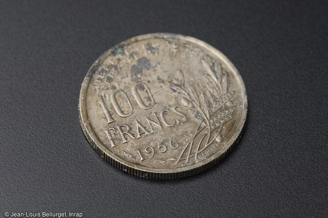 Pi&egrave;ce de monnaie de 100 francs, dat&eacute;e de 1956, d&eacute;couverte lors de la fouille de la Zac Pasteur &agrave; Besan&ccedil;on (Doubs) entre 2010 et 2011.