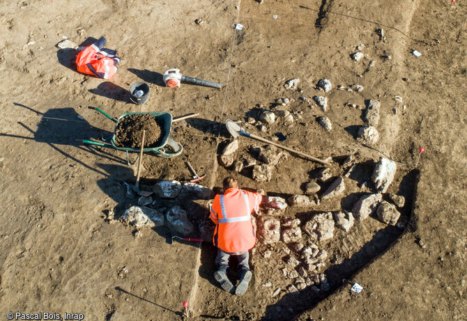 Fouille du soubassement d'un mur en pierre d'un b&acirc;timent du Bronze ancien &agrave; Saint-Geni&egrave;s-de-Fontedit (H&eacute;rault) en 2022. Une portion de mur permet de reconna&icirc;tre l'extr&eacute;mit&eacute; en abside d'un imposant b&acirc;timent mesurant 6 m de large pour une longueur qui devait d&eacute;passer 10 m. Seule les premi&egrave;res assises devaient &ecirc;tre en pierre. Ce mat&eacute;riau, qui offre une meilleure r&eacute;sistance, est souvent privil&eacute;gi&eacute; pour les parties basses des murs, les parties hautes &eacute;taient en bois et en terre crue. Cette d&eacute;couverte documente pour la premi&egrave;re fois la forme des maisons du d&eacute;but de la Protohistoire dans les plaines 