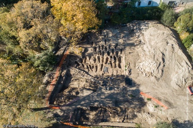 Vue a&eacute;rienne de la moiti&eacute; sud du site de fouille du quartier de Saint-Ferr&eacute;ol &agrave; Uz&egrave;s (Gard). L'emprise du site a permis l'&eacute;tude de pr&egrave;s de 200 s&eacute;pultures, orient&eacute;s ouest/est, implant&eacute;es en rang&eacute;es et quasi syst&eacute;matiquement install&eacute;es dans le rocher. 