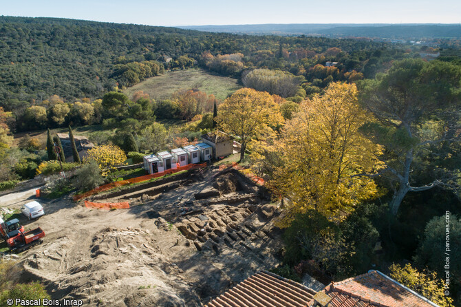 Vue a&eacute;rienne du site en cours de fouille du quartier Saint-Ferr&eacute;ol &agrave; Uz&egrave;s (Gard) avec la vall&eacute;e de l'Eure en arri&egrave;re-plan. Situ&eacute; dans un quartier p&eacute;ri-urbain mis en place &agrave; la p&eacute;riode R&eacute;publicaine (fin IIe av. J.-C. - 27 ap. J.-C.), sa fonction est encore &agrave; d&eacute;finir. Il a abrit&eacute; ensuite un vaste cimeti&egrave;re rupestre qui s'est d&eacute;velopp&eacute; entre les VIIe-XIIe si&egrave;cles. 