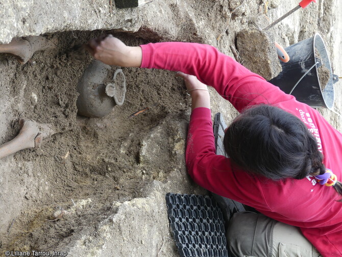 S&eacute;pulture en cours de fouille dans le cimeti&egrave;re rupestre (VIIe-XIIe si&egrave;cle) du quartier de Saint-Ferr&eacute;ol &agrave; Uz&egrave;s (Gard). Un pot en c&eacute;ramique est d&eacute;pos&eacute; au pied du d&eacute;funt. Une trentaine de pots globulaires, &agrave; usage domestique et de fabrication locale a &eacute;t&eacute; exhum&eacute;e des tombes. Contenant des cendres, de l'encens ou de l'eau banite, ils recevaient une pierre en guise de bouchon afin de prot&eacute;ger le contenu au moment du rebouchage de la tombe. 