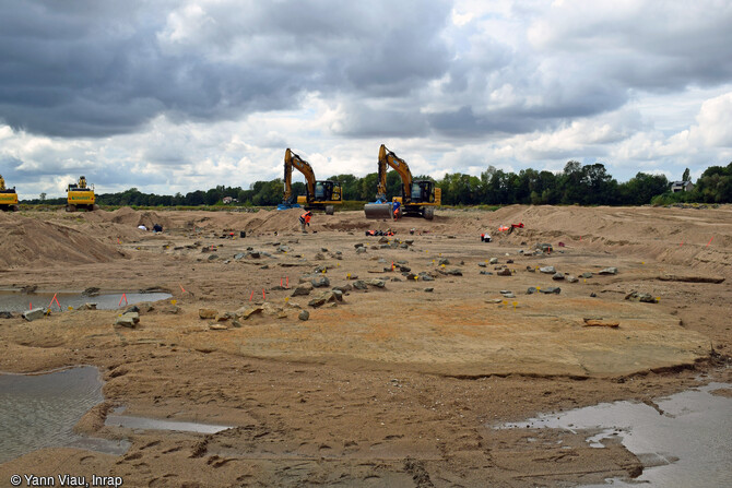 Vue en amont de la p&ecirc;cherie fixe du site n&deg; 2 de l'&icirc;le Poulas (Maine-et-Loire) en cours de fouille en 2022. Une multitude de blocs pars&egrave;ment la surface du niveau d'argile, au sommet duquel sont install&eacute;s les pi&egrave;ges &agrave; poissons. La pr&eacute;sence de ces pierres reste &eacute;nigmatique &agrave; ce stade de la fouille (origine naturelle ou anthropique) et ont-elles un lien avec la p&ecirc;cherie ? D'apr&egrave;s les premi&egrave;res datations, ces p&ecirc;cheries auraient fonctionn&eacute; au cours du XIIe si&egrave;cle. 