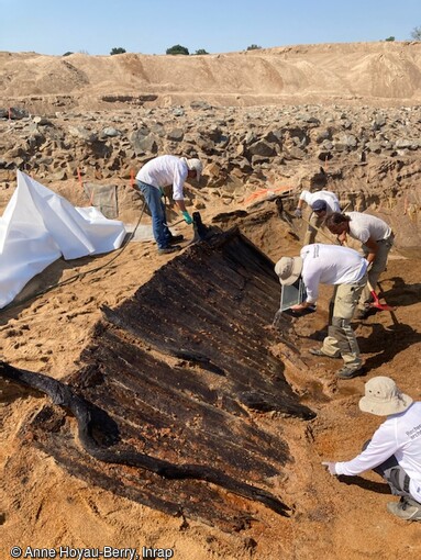 Arrosage des &eacute;paves des XVIIe-XVIIIe si&egrave;cles mises au jour de l'&icirc;le Coton, Ancenis (Loire-Atlantique) en 2022. Le bois doit &ecirc;tre maintenu humide pour des questions de conservation. Ces bateaux en ch&ecirc;ne avaient une &eacute;tanch&eacute;it&eacute; assur&eacute;e par un syst&egrave;me de  pl&acirc;trage  (intercalage de mousse v&eacute;g&eacute;tale entre les planches).