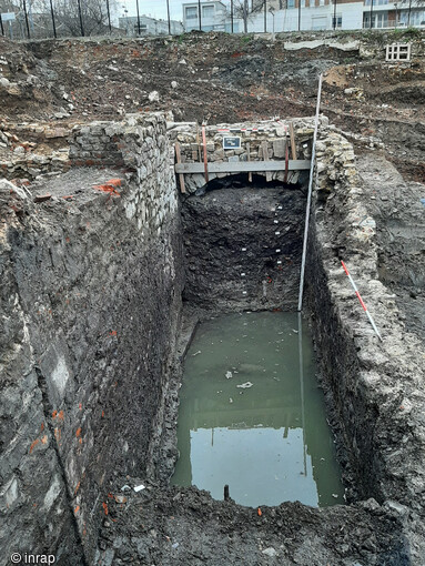 Canal de dérivation de la rivière Sambre et pont du 15e siècle mis au jour à Maubeuge (Nord) en 2023. Le niveau de l’eau correspond globalement au fond du canal. Les remblais stratifiés d’abandon du canal durant le 16e siècle sont visibles sous l’arche du pont.