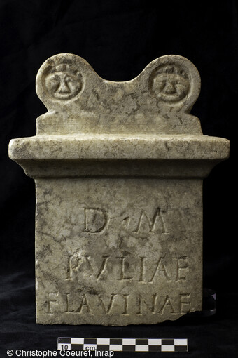 Autel en marbre portant l&rsquo;&eacute;pitaphe de Iulia Flavina et de sa situation dans le comblement d'une tombe de la n&eacute;cropole antique (1er au 3e si&egrave;cle) d&eacute;couverte &agrave; Narbonne (Aude).Elle a livr&eacute; des vestiges fun&eacute;raires exceptionnels tant par leur nombre (pr&egrave;s de 500 tombes) que par leur &eacute;tat de conservation. La plupart des fosses abritent principalement des urnes fun&eacute;raires, la cr&eacute;mation &eacute;tant la pratique courante pour la p&eacute;riode, ainsi que du mobilier d'accompagnement.   