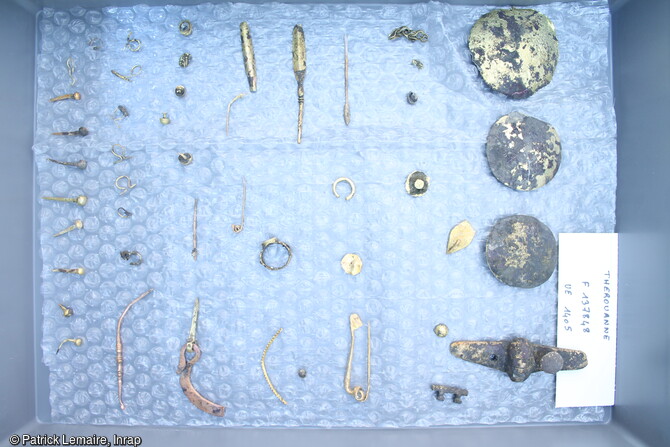 Objets dorés (épingle, agrafes, bague, appliques...) découverts dans le fond du canal découverts à Thérouanne (Pas-de-Calais).Le site, préservé par les alluvions, a livré les vestiges d'un canal aménagé, d'un atelier de verrier et un abondant mobilier (métal, cuir, os fragments de meule) dans un remarquable état de conservation.