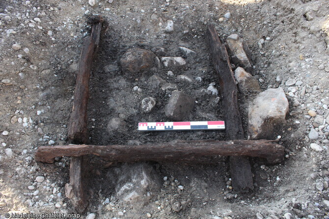 Base du coffrage d'un puit médiéval (Xe s.) constituée de planches de chêne assemblées à mi-bois formant un conduit de plan carré. Seule sa dernière assise était conservée. Sur son pourtour, les planches étaient maintenues par une couronne de moellons constitués en partie d’éléments récupérés (pierres volcaniques et fragments de meules), cerclée elle-même par des galets.