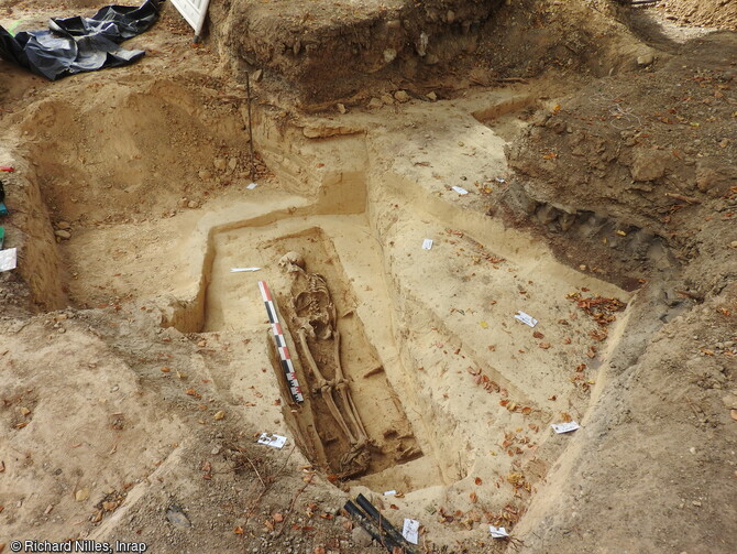 Vue g&eacute;n&eacute;rale d'une des s&eacute;pultures d&eacute;couverte sur le site de Strasbourg (Bas-Rhin)et attribu&eacute;e au Haut-Empire ( vers 250 ap. J.-C.). Elle pr&eacute;sente un individu adulte masculin de plus de 50 ans. Les limites observ&eacute;es (200x50 cm) ainsi que la pr&eacute;sence de traces de bois et de 17 clous dispos&eacute;s de part et d&rsquo;autre du squelette d&eacute;limitent une surface rectangulaire ne laissant que peu de doutes quant &agrave; la pr&eacute;sence initiale d&rsquo;un cercueil clou&eacute; en bois, ajust&eacute; &agrave; la morphologie de d&eacute;funt.