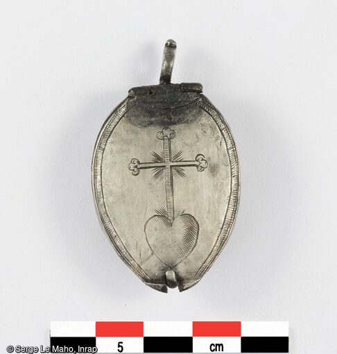 Pendentif reliquaire en argent découvert dans la sépulture 618 du cimetière du XVIIIe siècle à Yvetot (Seine-Maritime). Ce pendentif a été  retrouvé sur l'abdomen d'un homme âgé ; il était vraisemblablement dans la poche droite de son vêtement. Son contenu a été étudié. 