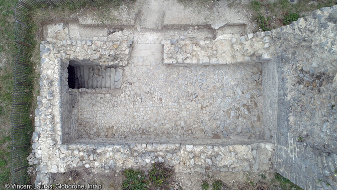 Vue zénithale du logis du château de Clermont-L'Hérault (Hérault) en 2023. Ce logis de plan rectangulaire a été occupé jusqu'au milieu du XVIIe siècle. La trémie d'escalier en haut à gauche, conduit à une pièce voûtée tardivement installée dans l'étage de soubassement. 