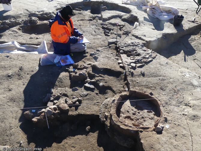 La maison à abside de l'âge du Fer en cours de fouille à Béziers (Hérault) en 2023. Au premier plan le four, suivis du foyer. Mesurant 7,6 m de long et 3 m de large, cette maison excavée a conservé d'épaisses séquences stratigraphiques offrant la possibilité d'observer ses aménagements domestiques. Avec une superficie de 20m2, elle s'inscrit dans la moyenne de celles connues dans la Midi de la Gaule à l'époque protohistorique. 