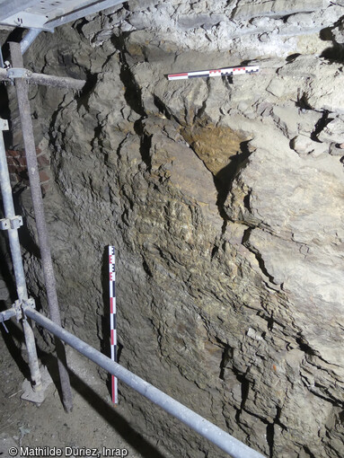 Détail du substrat rocheux sous la façade occidentale de l'église du XIVe siècle de Sainte-Croix-en-Jaretz (Loire). L'église est établie en limite nord-est d'un promontoire rocheux. La nature de ce substrat a été identifiée comme un socle schisteux. Plusieurs éléments convergent vers une exploitation de ce rocher dans l'intérêt du bâtiment. 