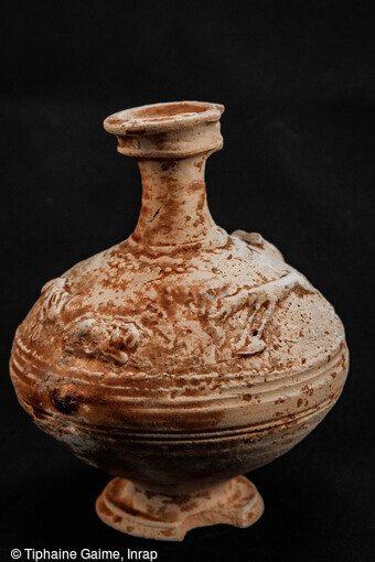 Cruche avec un d&eacute;cor de chasse pr&eacute;sentant une d&eacute;coupe sur le bord, le pied et l'anse, d&eacute;couverte dans une s&eacute;pulture de l'ensemble fun&eacute;raire antique de Saint-Vulbas (Ain). Plusieurs traitements particuliers sont visibles sur les vases, allant &agrave; la d&eacute;coupe du bord &agrave; l'arrachement des cols ou des anses avec plusieurs gestes sur le m&ecirc;me vase.