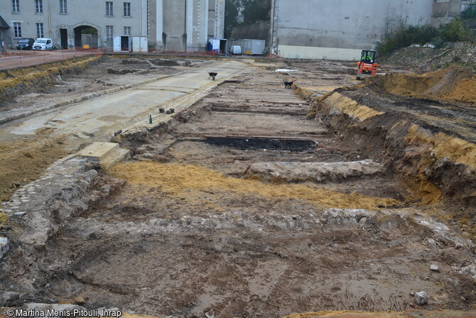 La rue du Pont du Gast des ann&eacute;es 1960 retrouv&eacute;e dans la partie centrale de la fouille de l'&icirc;lot Saint-Vincent &agrave; Blois (Loir-et-Cher), avec les fondations des maisons jadis en front de rue ; &agrave; l'arri&egrave;re plan, l'Orangerie des jardins royaux (mur aveugle &agrave; droite) et le chevet de l'&eacute;glise Saint-Vincent (eu centre). 