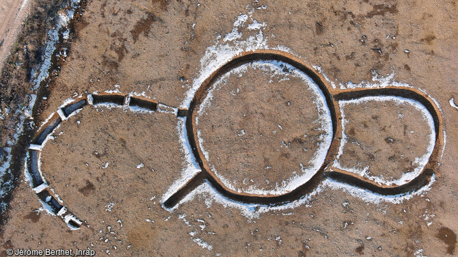 Vue aérienne du triple enclos du Néolithique à Marliens (Côte d'Or). Au centre du monument se trouvait un enclos circulaire de 11 m de diamètre. A droite un enclos en forme de fer à cheval de 8 m de long et à gauche un enclos ouvert qui s'adosse à l'enclos central. La présence d'une couche de graviers, observée dans le comblement de des deux enclos latéraux, atteste de l'existence d'une palissade. Ce type de monument semble inédit. 