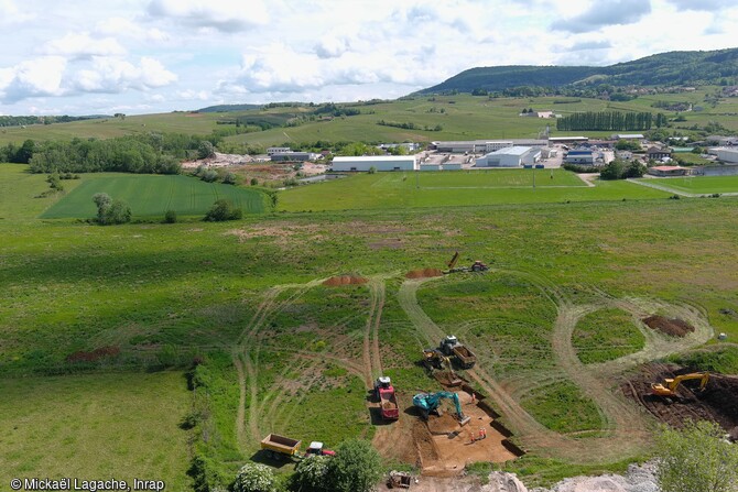 Vue aérienne du secteur de la fouille, et décapage en cours à Arbois (Jura). Située sur la rive droite de la Cuisance, l'opération de fouille concerne une vaste plaine alluviale à la frontière entre les zones montagneuses du Jura et la plaine bressane.  