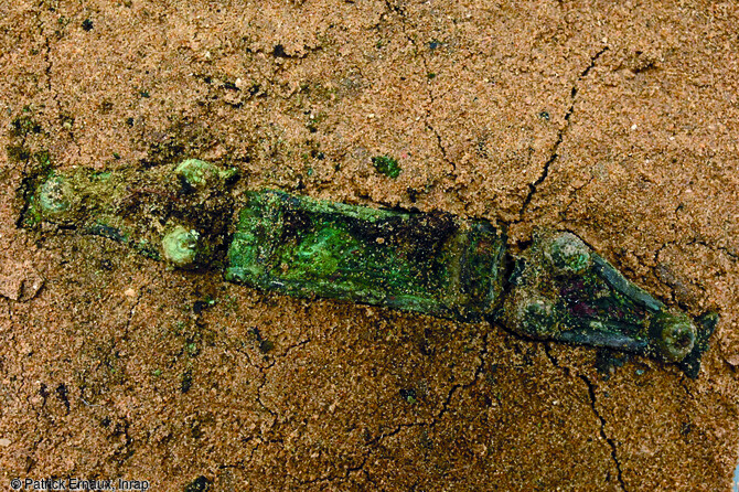 Éléments d'une ceinture en alliage cuivreux à décor de bossettes provenant d'une inhumation à La Flotte sur l'île de Ré (Charente-Maritime). L'observation du mobilier retrouvé au cours de la fouille tend à rapprocher celui-ci de la culture matérielle des sociétés de la mer du Nord et n'a pas d'équivalent en France ce qui rend les comparaisons difficiles. Les analyses de ces matériaux permettront de connaître leur origine.