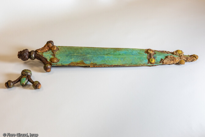 Épée courte à poignées à antennes entièrement ornée découverte dans une sépulture datée de l'âge du fer.Les travaux de stabilisation du mobilier funéraire révèlent aujourd'hui des parures métalliques et des armes d’une facture exceptionnelle qui ont peu d’équivalent en Europe.