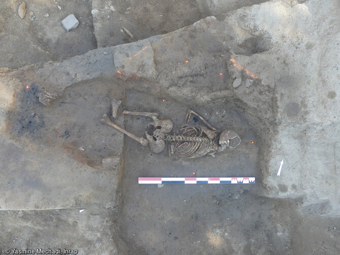    Vue d’un squelette inhumé sur le ventre, tête à l’est, dans le creusement d’un bûcher funéraire après son abandon, Strasbourg (Bas-Rhin), 2024.             